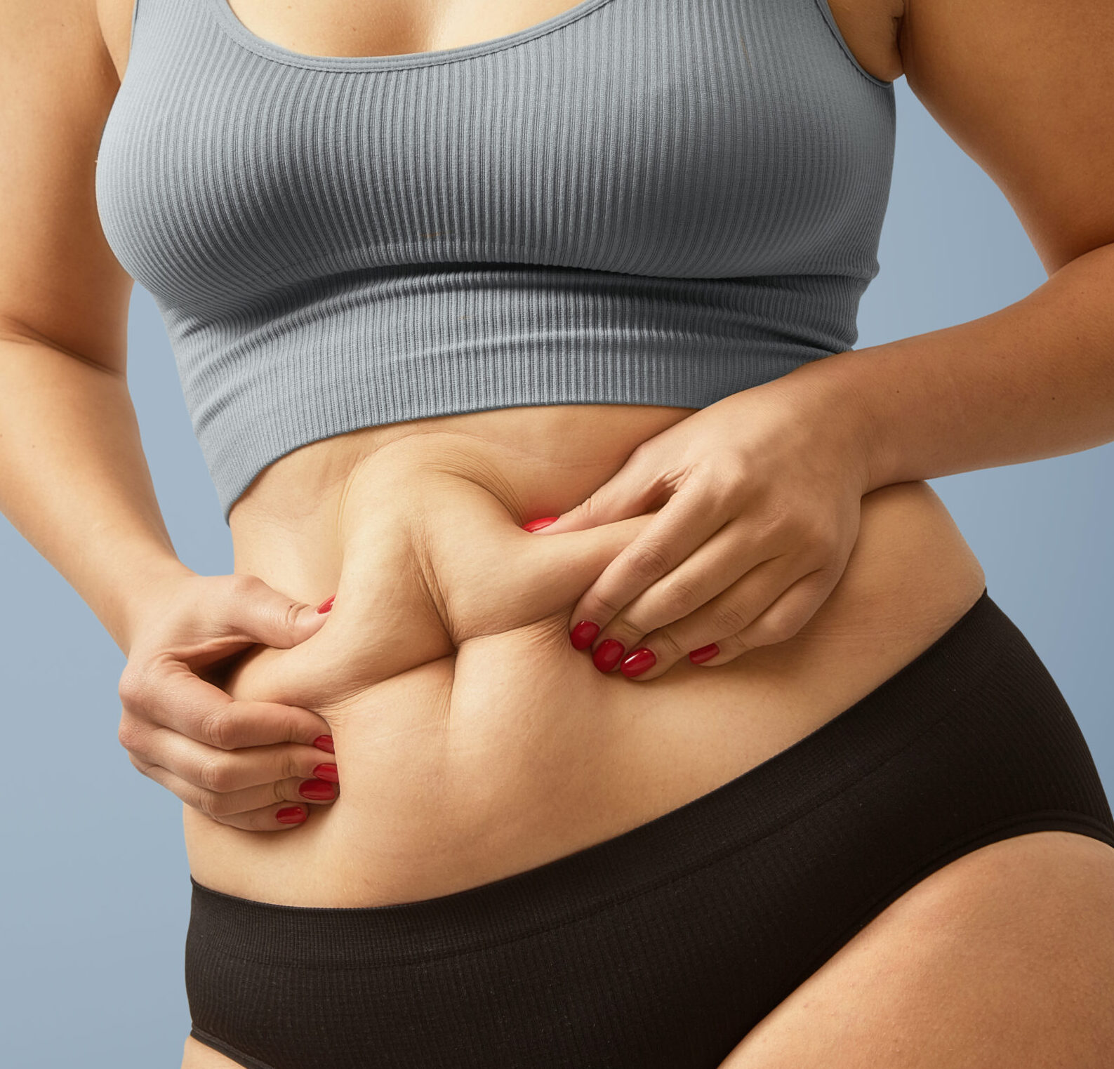 Woman body fat belly. Obese woman hands holding excessive tummy fat. Change diet lifestyle concept to shape up healthy stomach muscle. Studio anonymous shot photo of body parts.